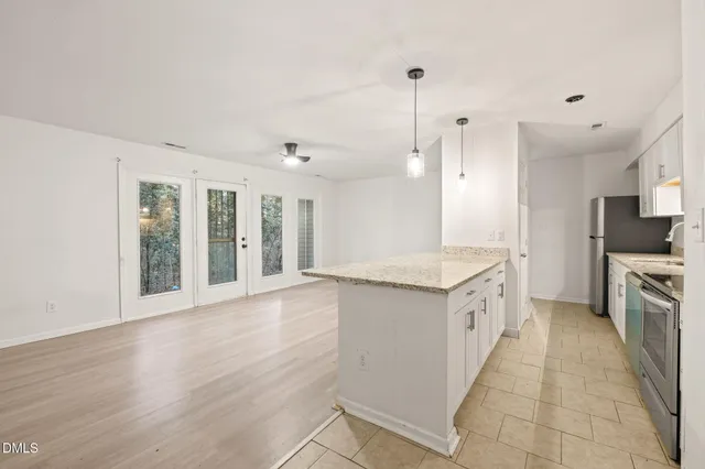 a large kitchen with granite countertop a large counter top stainless steel appliances and cabinets