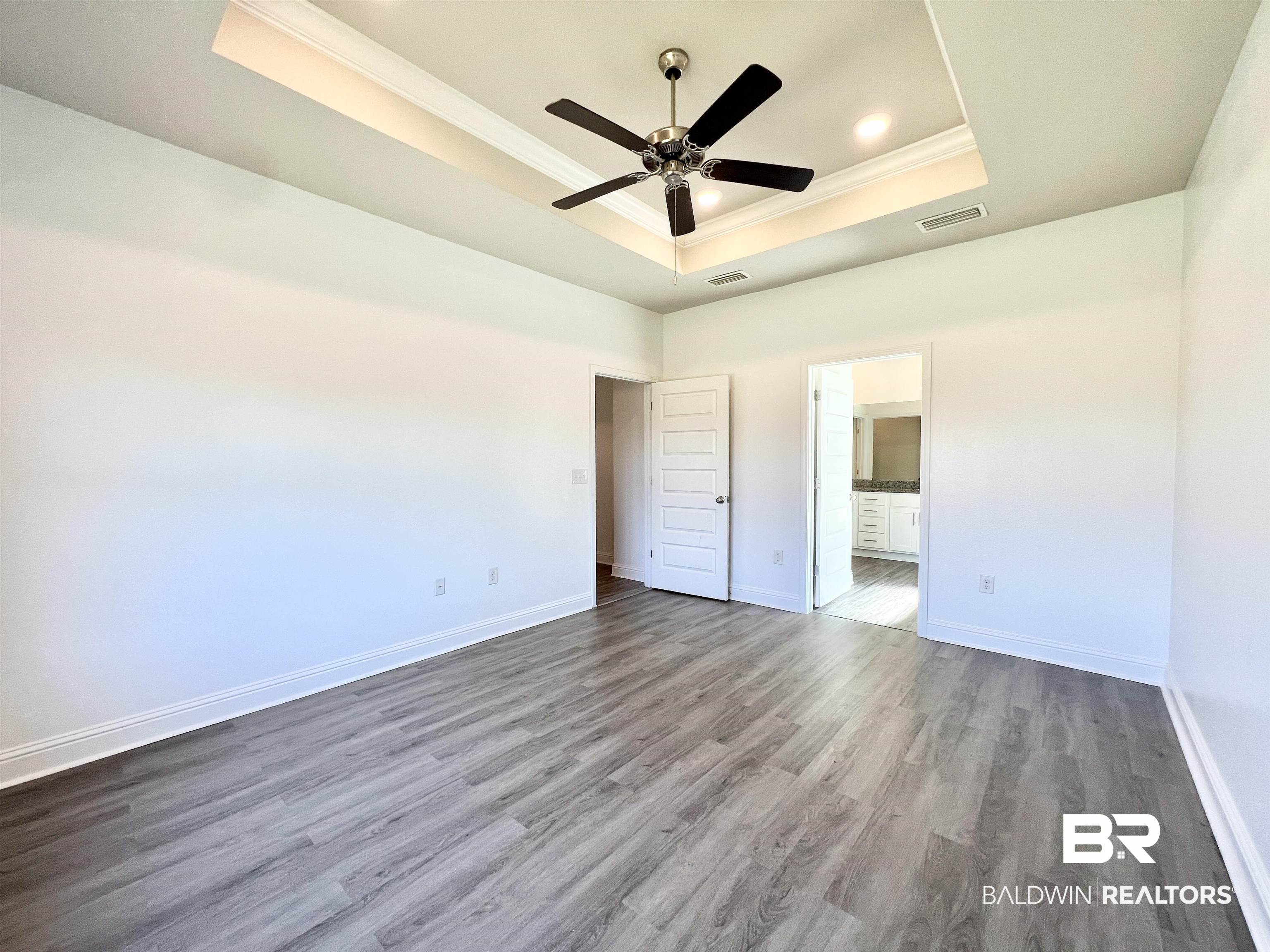 24785 Slater Mill Road Daphne, AL 36526 - Photo 26 of 46 Unfurnished bedroom with ceiling fan, ensuite bathroom, a tray ceiling, and hardwood / wood-style floors
