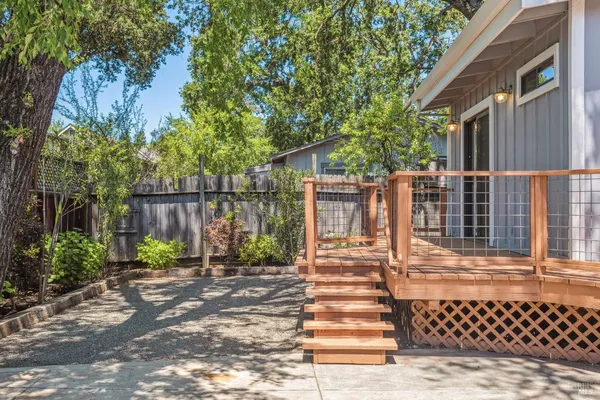 a view of a brick house with a large tree and wooden fence