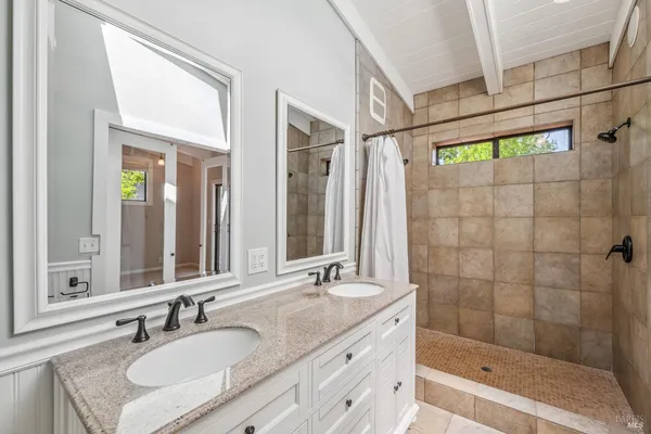 a bathroom with a granite countertop sink a mirror a glass door and shower