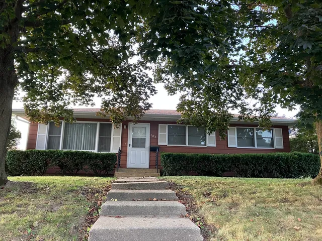 a front view of a house with plants and trees