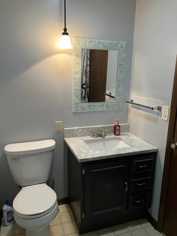a bathroom with a granite countertop toilet sink and mirror