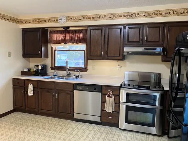 a kitchen with stainless steel appliances granite countertop a stove a sink and a microwave