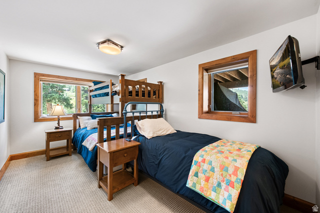 1782 Pine Loop Road Coalville, UT 84017 - Photo 17 of 52 Wall-mounted television, wood-trimmed windows, built-in bunk beds, light-toned carpet, and a flush-mount ceiling light fixture