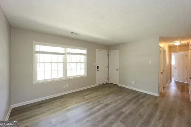 an empty room with wooden floor and windows