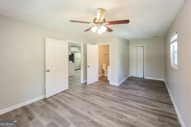 a view of an empty room with wooden floor and a ceiling fan
