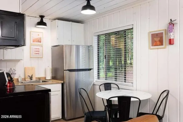 a kitchen with stainless steel appliances a refrigerator a sink a stove a dining table and chairs