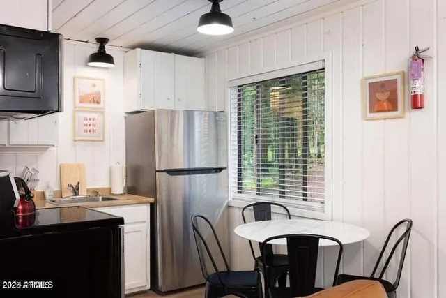 a kitchen with stainless steel appliances a refrigerator a sink a stove a dining table and chairs