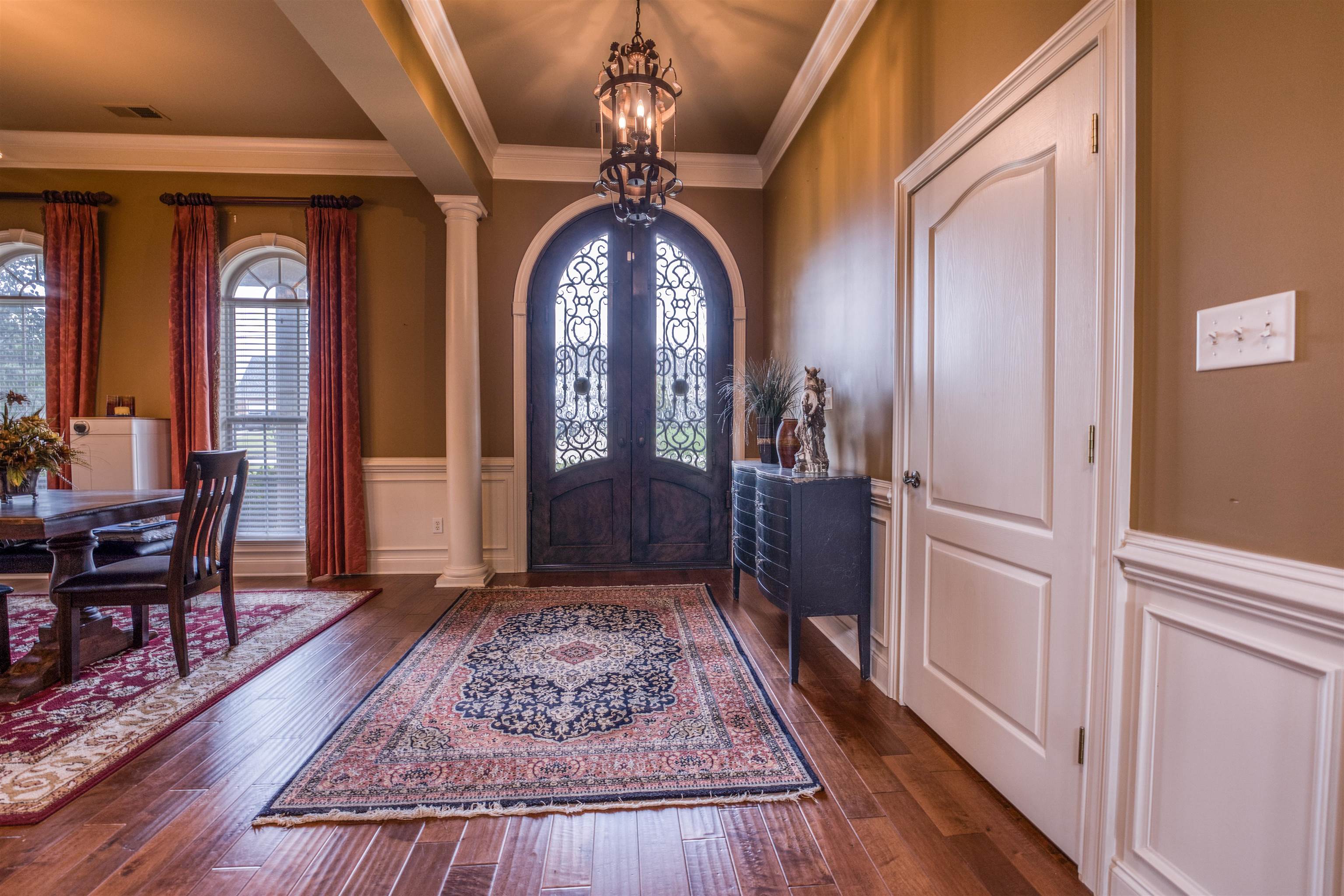 215 Walker Lake Road Atoka, TN 38004 - Photo 5 of 38 Entryway featuring crown molding, decorative columns, dark wood-type flooring, and a notable chandelier