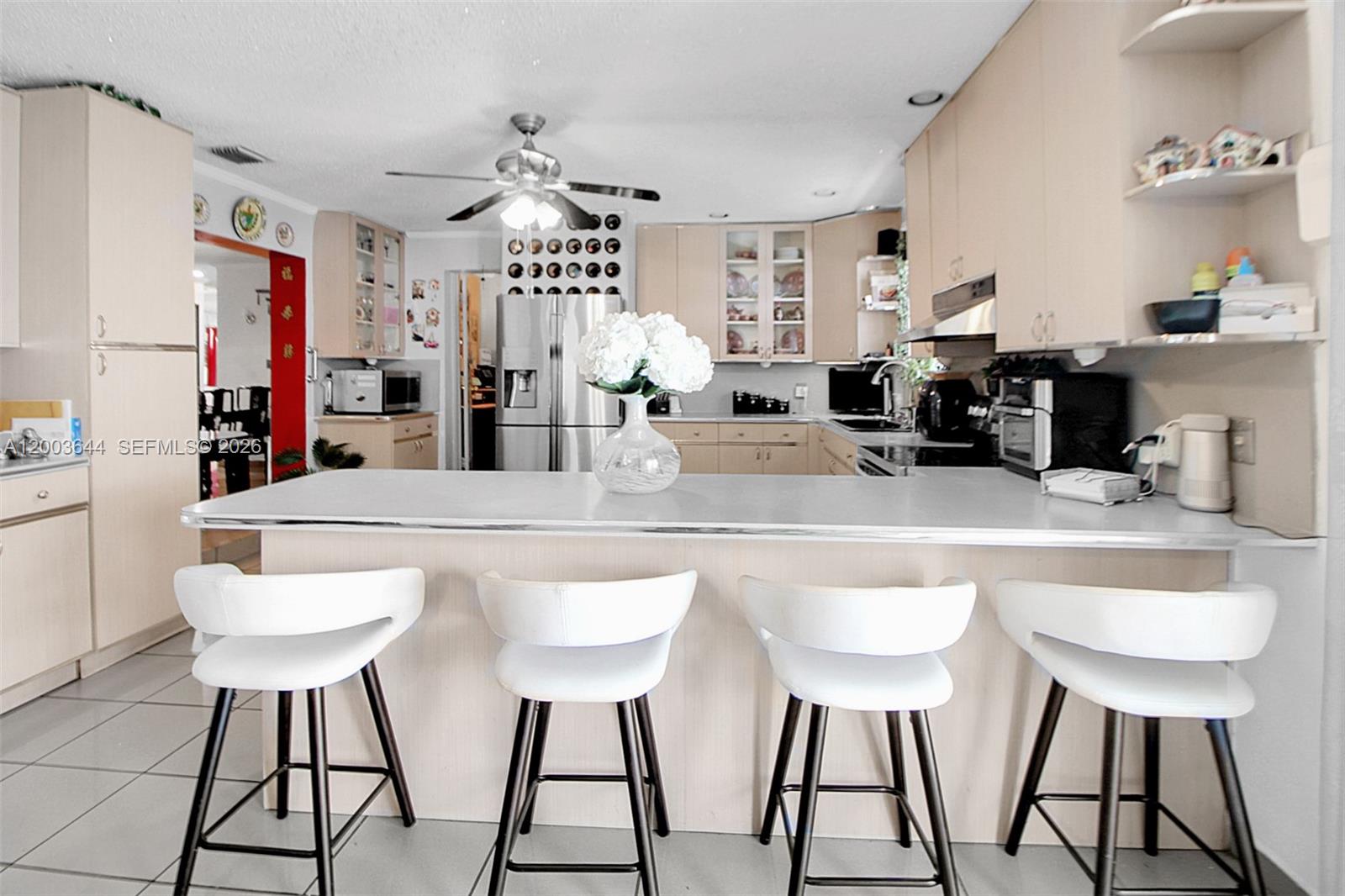 19100 Southwest 125th Avenue Miami, FL 33177 - Photo 18 of 46 a kitchen with stainless steel appliances kitchen island granite countertop a dining table chairs and a refrigerator