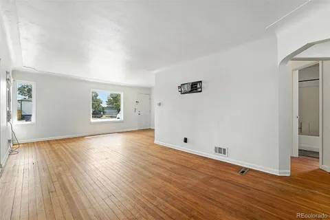 an empty room with wooden floor and windows