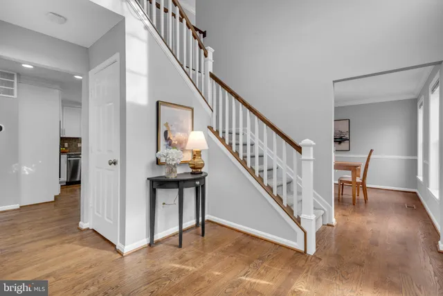 a view of an empty room with wooden floor and a kitchen