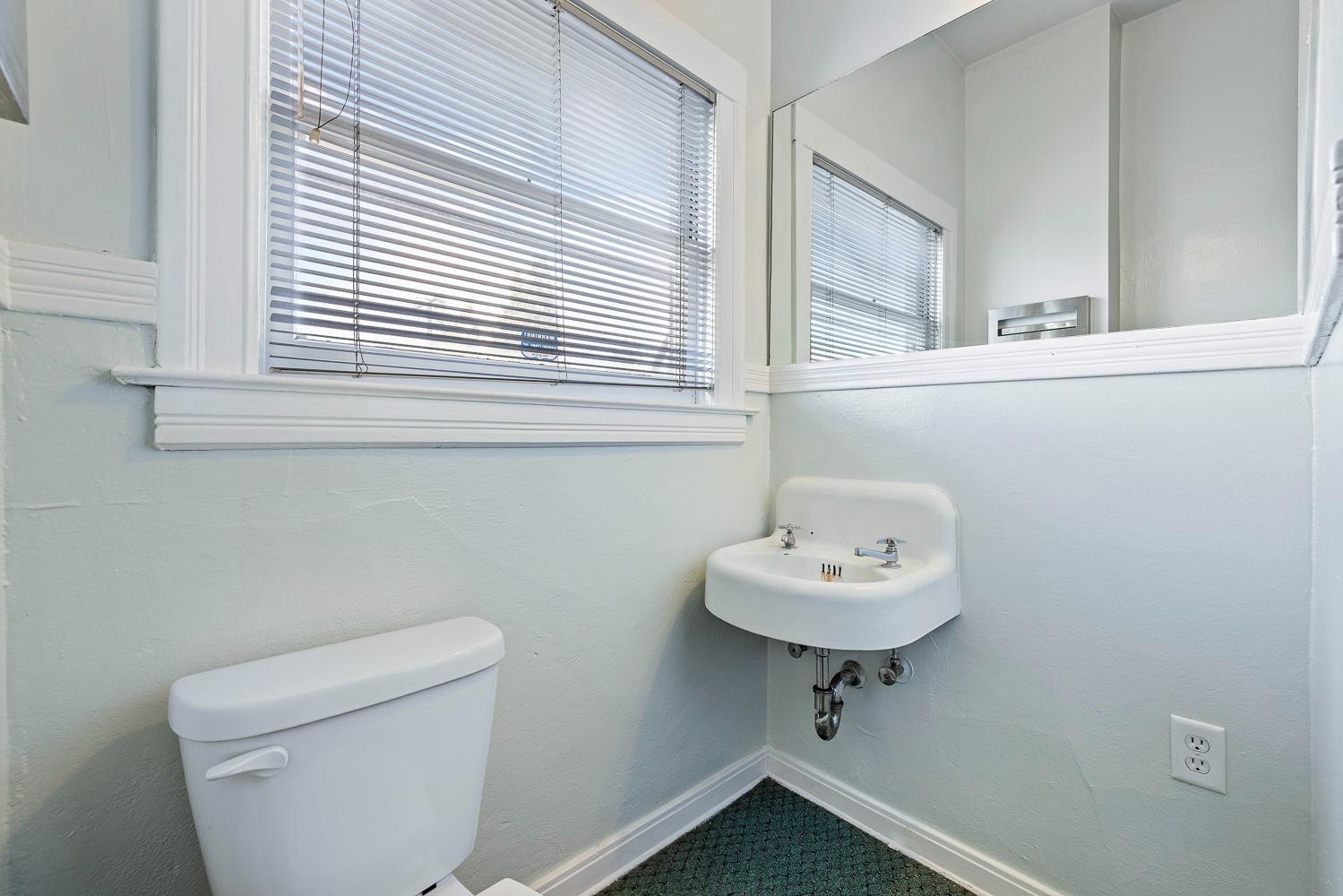 235 North Fulton Street Fresno, CA 93701 - Photo 26 of 43 a bathroom with a sink a mirror and a toilet
