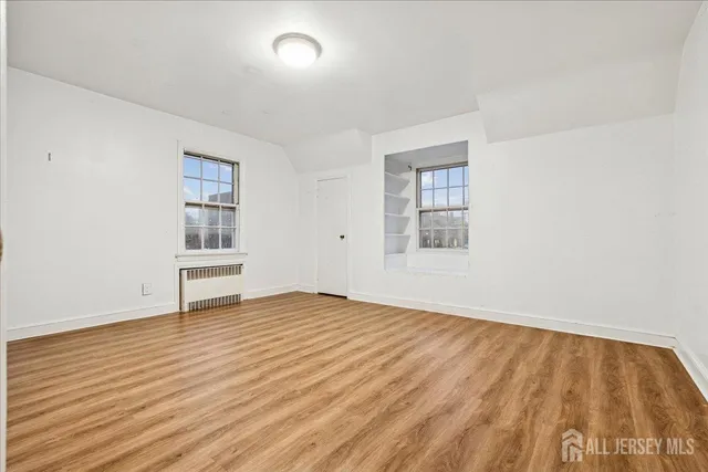 an empty room with wooden floor and window