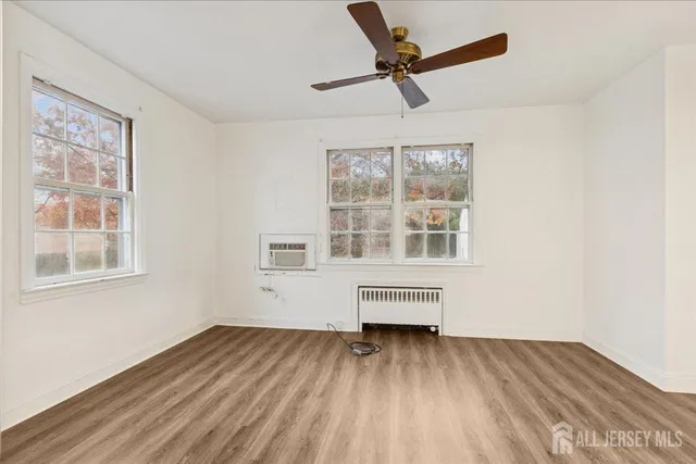 an empty room with wooden floor fan and windows