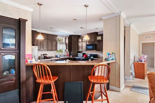 a kitchen with stainless steel appliances granite countertop table chairs and a refrigerator