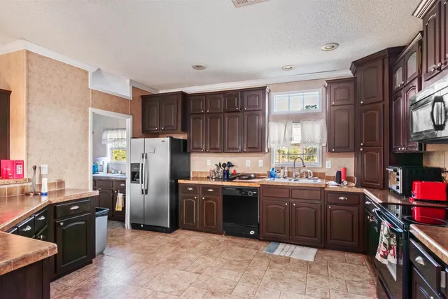 a kitchen with stainless steel appliances granite countertop a stove top oven a sink dishwasher a refrigerator and cabinets with wooden floor