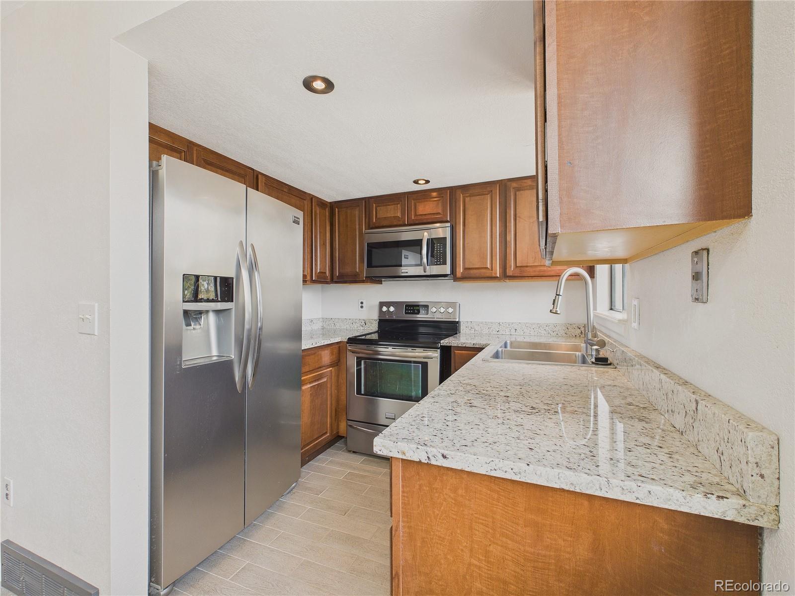 6725 West 84th Way, Unit 72 Arvada, CO 80003 - Photo 4 of 20 a kitchen with stainless steel appliances granite countertop a sink stove and refrigerator