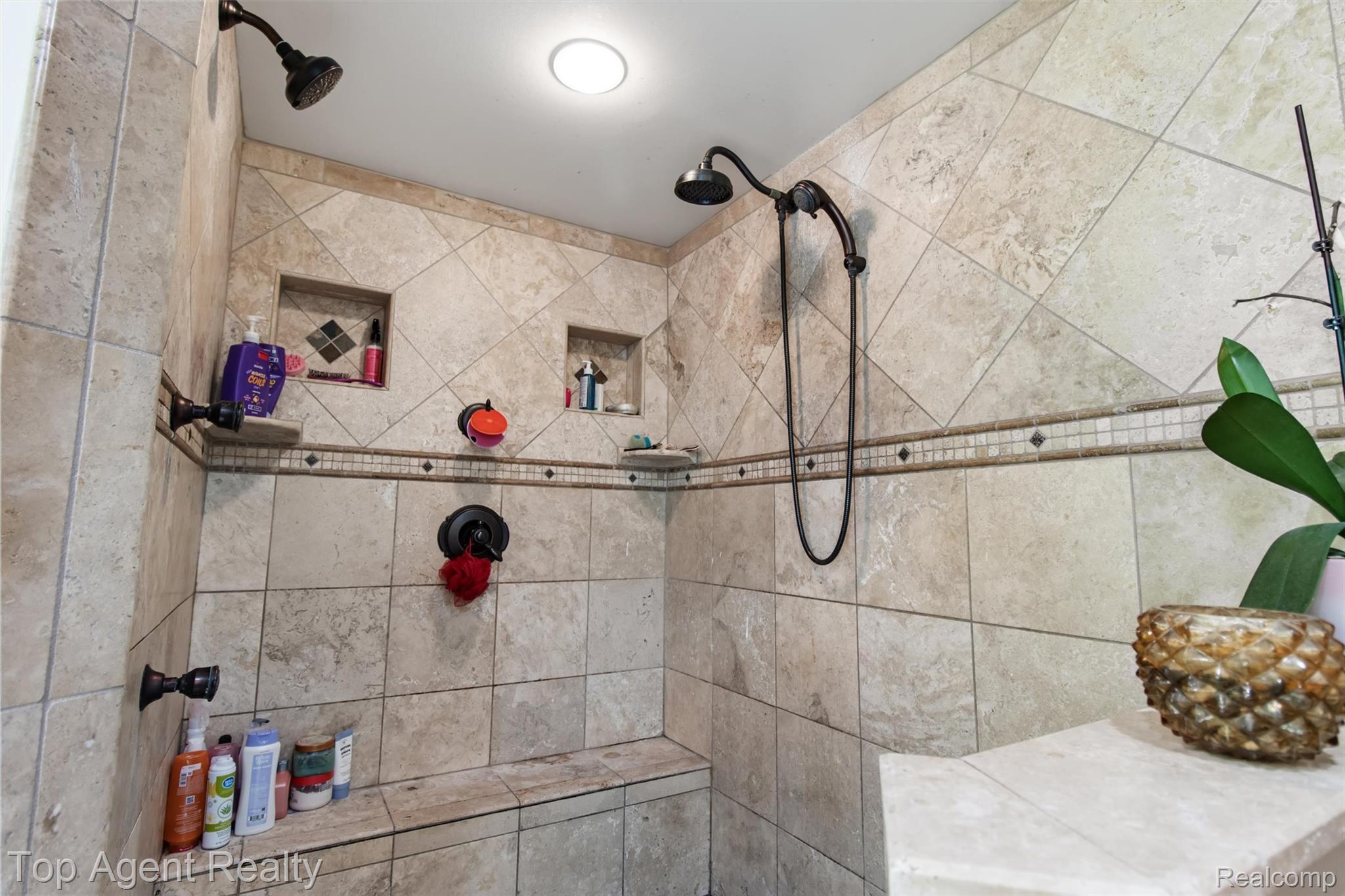 32341 Woody Road Fraser, MI 48026 - Photo 25 of 47 Spacious tiled shower featuring dual shower heads, a built-in bench, two recessed wall niches, and decorative accent tile