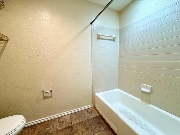 a bathroom with a granite countertop bathtub shower and toilet