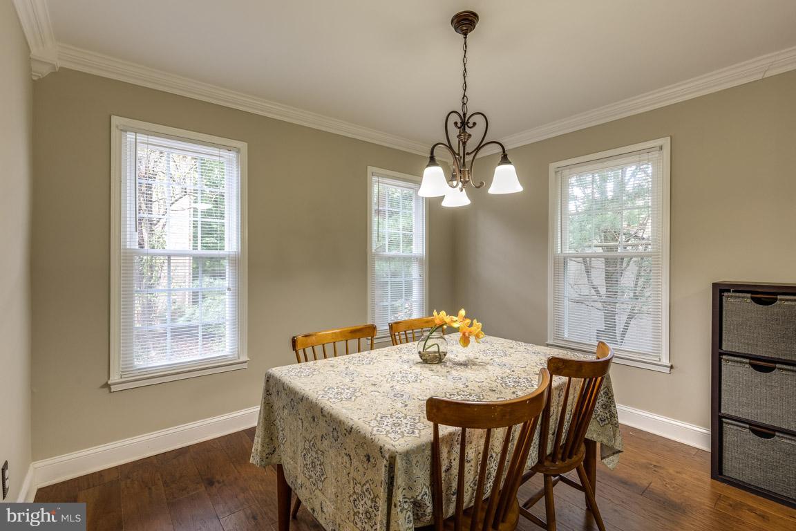11841 Dunlop Court Reston, VA 20191 - Photo 9 of 30 a dining room with wooden floor a chandelier a wooden table and chairs