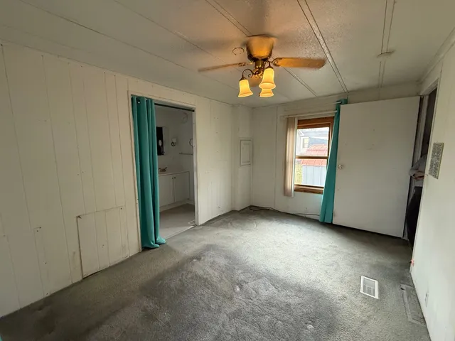 an empty room with windows and ceiling fan