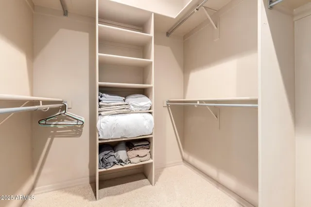 a view of walk in closet with clothes and shoes