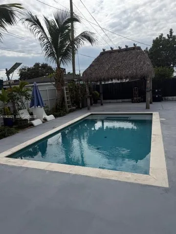 a view of swimming pool with lawn chairs and plants