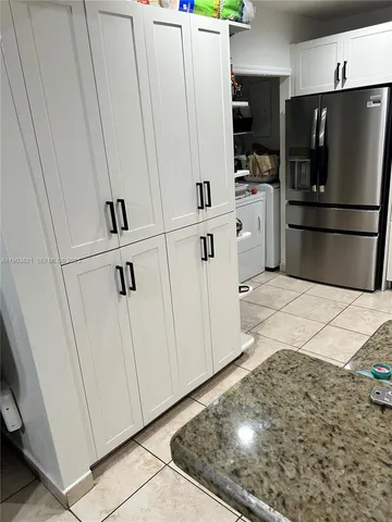 a kitchen with white cabinets and refrigerator