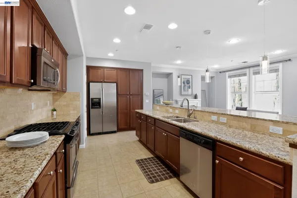 a kitchen with stainless steel appliances granite countertop a sink stove and refrigerator