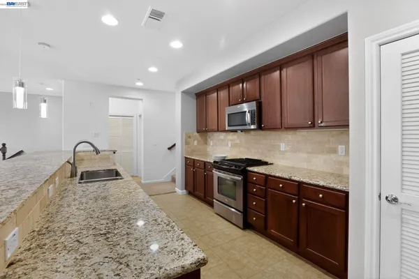a kitchen with stainless steel appliances granite countertop a stove sink and cabinets