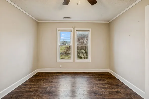 an empty room with wooden floor and windows