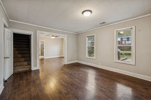 an empty room with wooden floor closet and windows