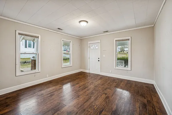 a view of an empty room with wooden floor and a window