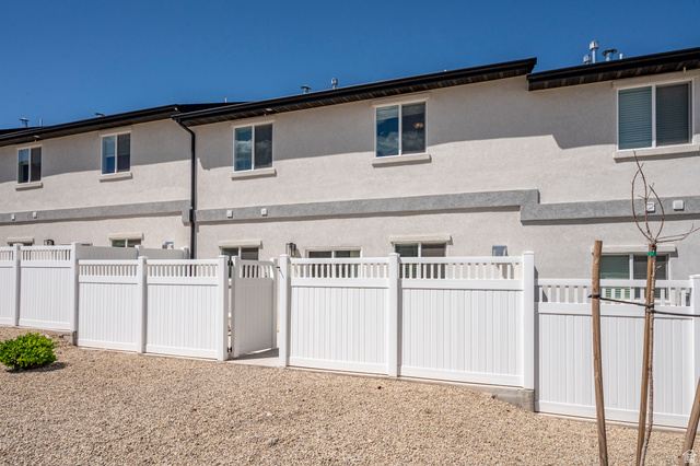 668 East Fiddlers Canyon Road, Unit 6 Cedar City, UT 84721 - Photo 30 of 36 Rear exterior showcasing white privacy fencing, a gate, and a gravel ground cover