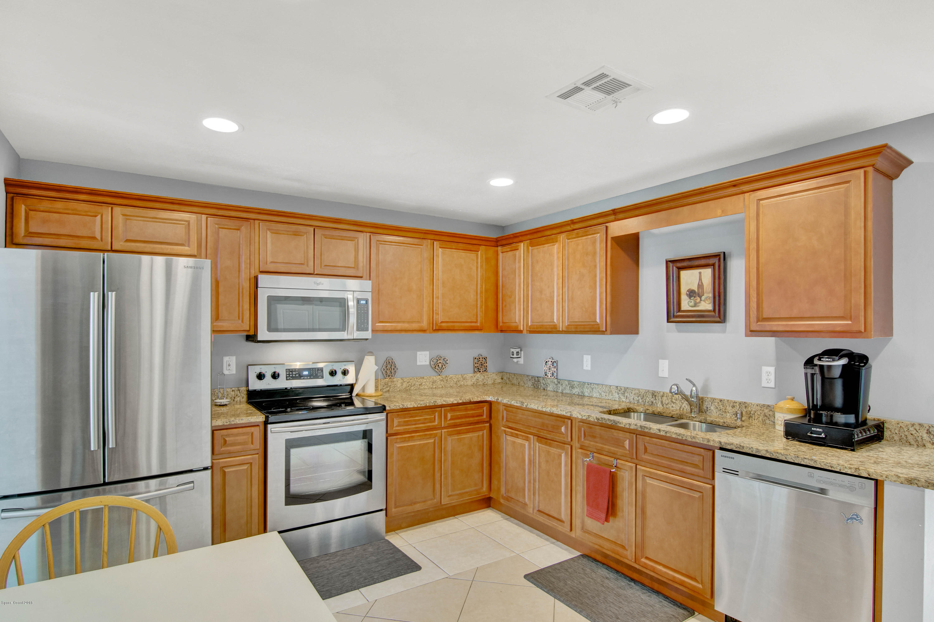 2512 Post Road Melbourne, FL 32935 - Photo 12 of 25 a kitchen with stainless steel appliances granite countertop a refrigerator a sink dishwasher a stove and white cabinets with wooden floor