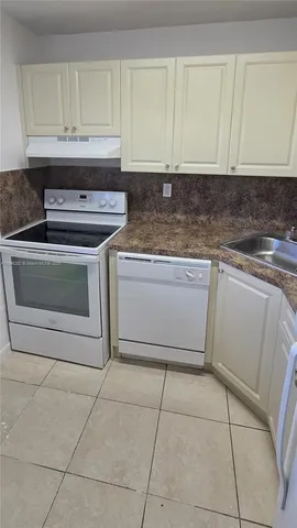 a kitchen with granite countertop a stove a sink and cabinets
