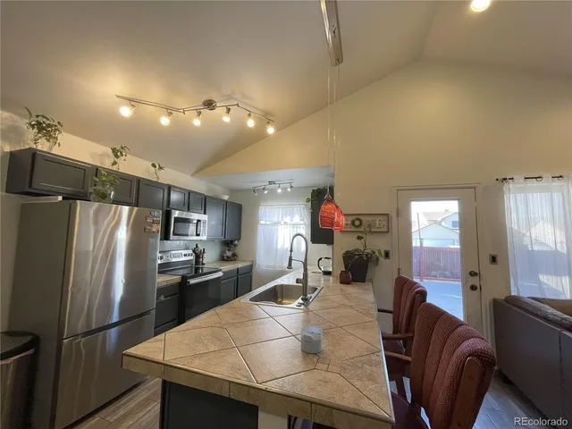 a kitchen with stainless steel appliances refrigerator dining table and chairs