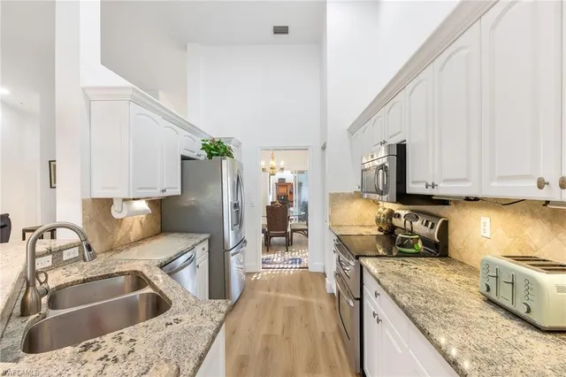 a kitchen with granite countertop a sink a counter top space appliances and cabinets