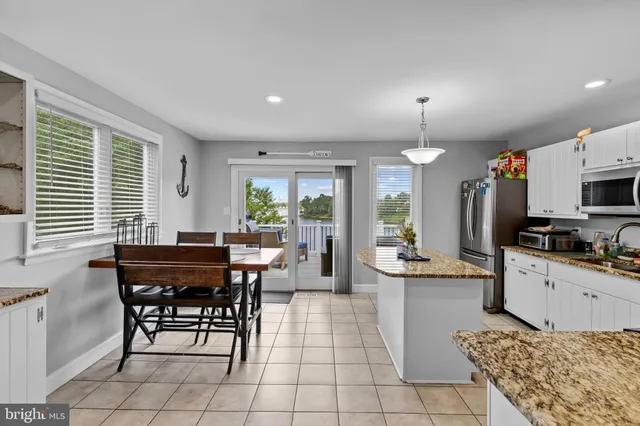 a kitchen with stainless steel appliances kitchen island granite countertop a sink a stove a dining table and chairs with wooden floor