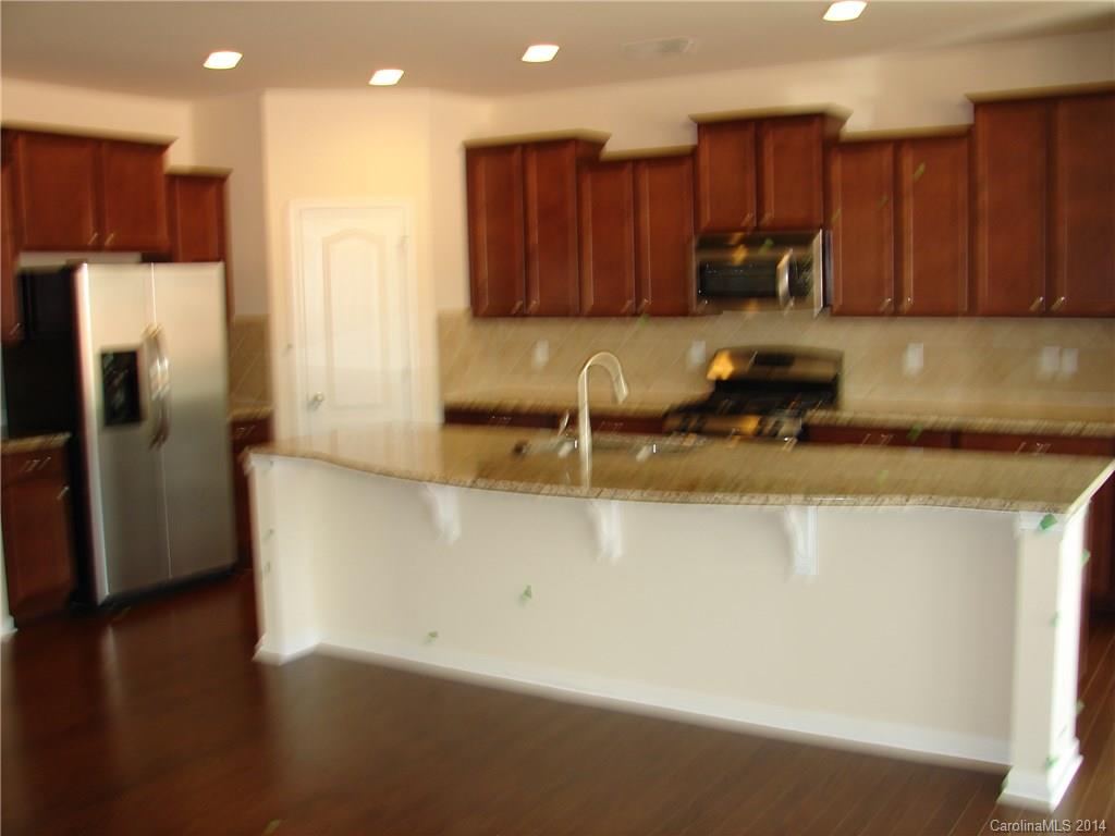 4316 Perth Road, Unit 290 Indian Land, SC 29707 - Photo 5 of 11 a kitchen with stainless steel appliances granite countertop a refrigerator a sink a stove a microwave and island with wooden floor