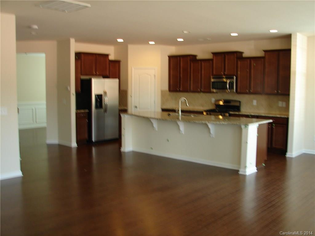 4316 Perth Road, Unit 290 Indian Land, SC 29707 - Photo 6 of 11 a kitchen with stainless steel appliances granite countertop a refrigerator a sink a stove and a microwave with wooden floor
