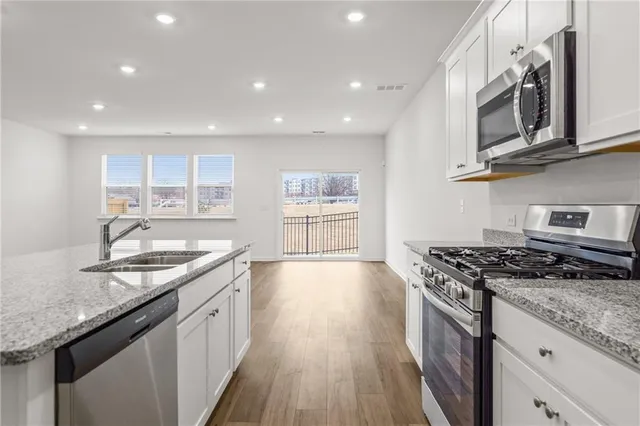 a kitchen with stainless steel appliances granite countertop a sink stove and cabinets