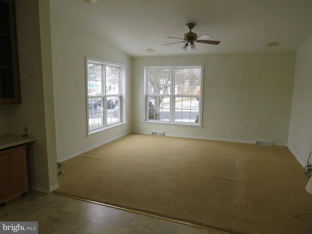 an empty room with windows and a ceiling fan