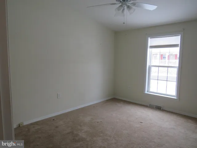 an empty room with a window and a ceiling fan