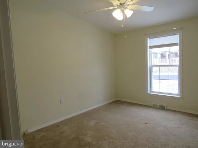 an empty room with a window and a fan