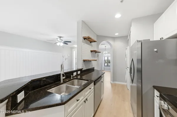 a kitchen with granite countertop a sink a refrigerator and cabinets