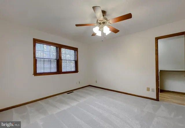 an empty room with windows and ceiling fan