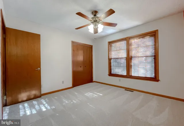 a view of an empty room with chandelier fan and windows