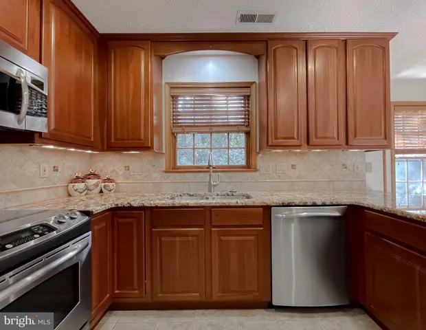 a kitchen with granite countertop a sink stove and cabinets